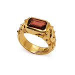 Gold ring with a red gemstone on a white background