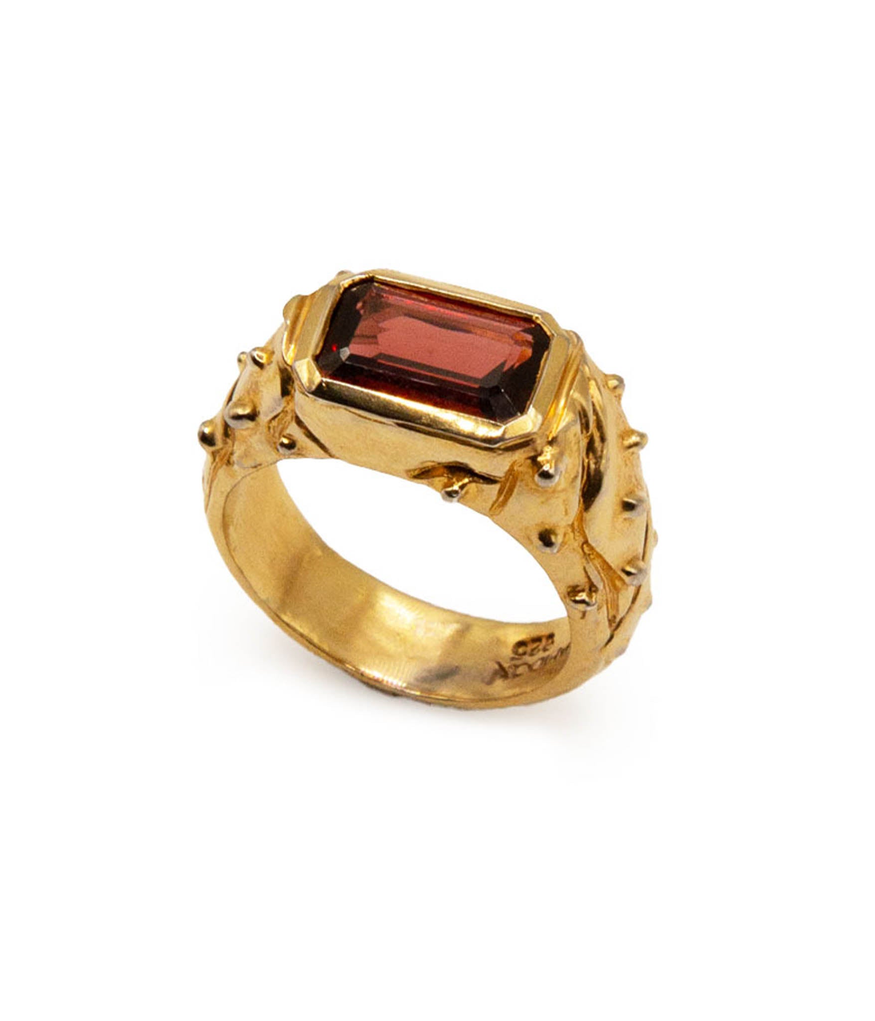 Gold ring with a red gemstone on a white background