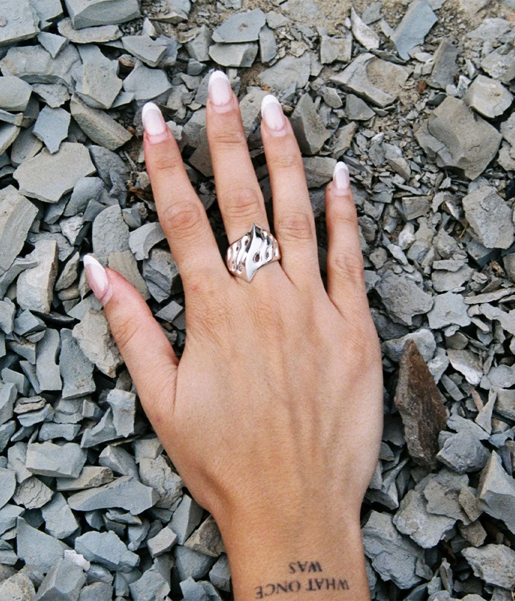 Hand wearing a silver ring on a bed of small stones