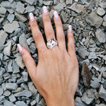 Hand wearing a silver ring on a bed of small stones