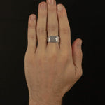 Hand wearing a silver ring on a black background