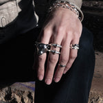 Close-up of a hand wearing multiple silver rings with a dark background
