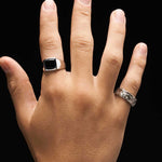 Hand wearing two rings on a black background