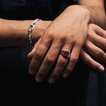 Close-up of hands with a ring and bracelet on a dark background