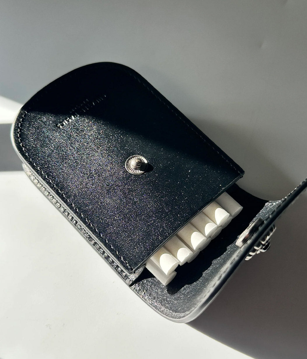 Black leather case with a metallic button on a white surface