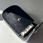 Black leather case with a metallic button on a white surface