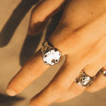 Close-up of a hand wearing a decorative ring with a textured band.