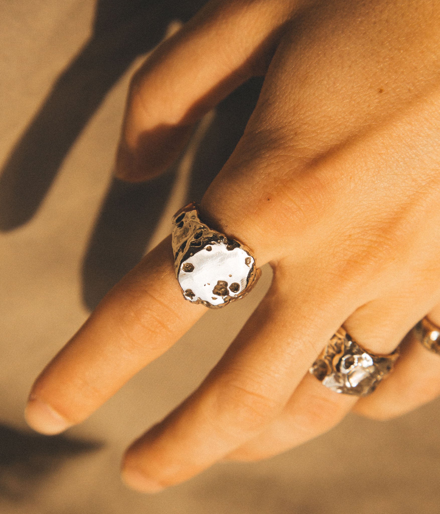 Close-up of a hand wearing a decorative ring with a textured band.