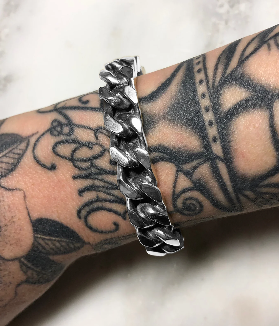 Silver chain bracelet on a wrist with tattoos