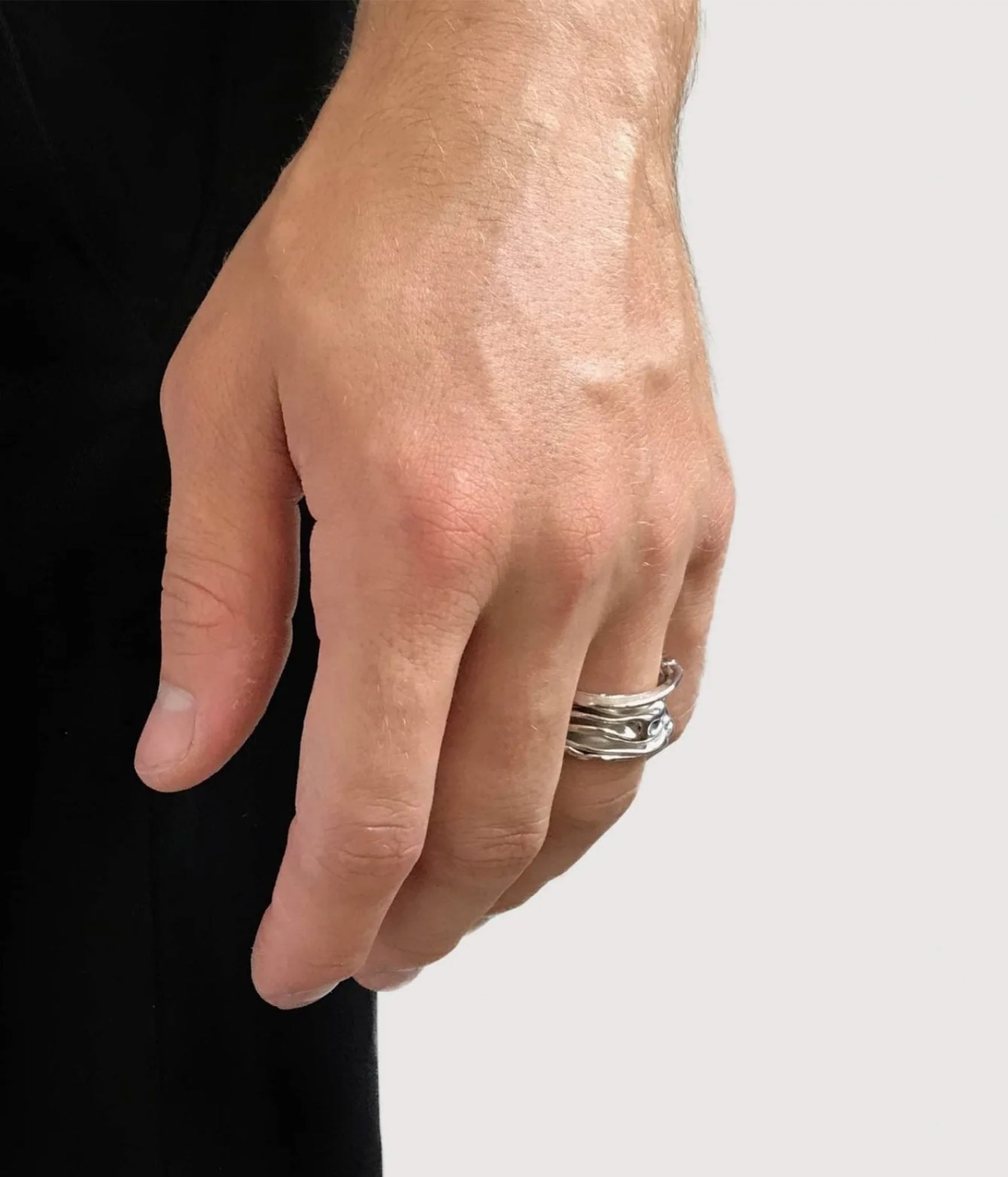 Hand wearing a silver ring on a plain background