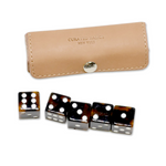 A set of five black and brown tortoiseshell dice with white pips, shown with a beige leather case embossed with 'CURATED BASICS NEW YORK' and a silver snap closure, on a white background.