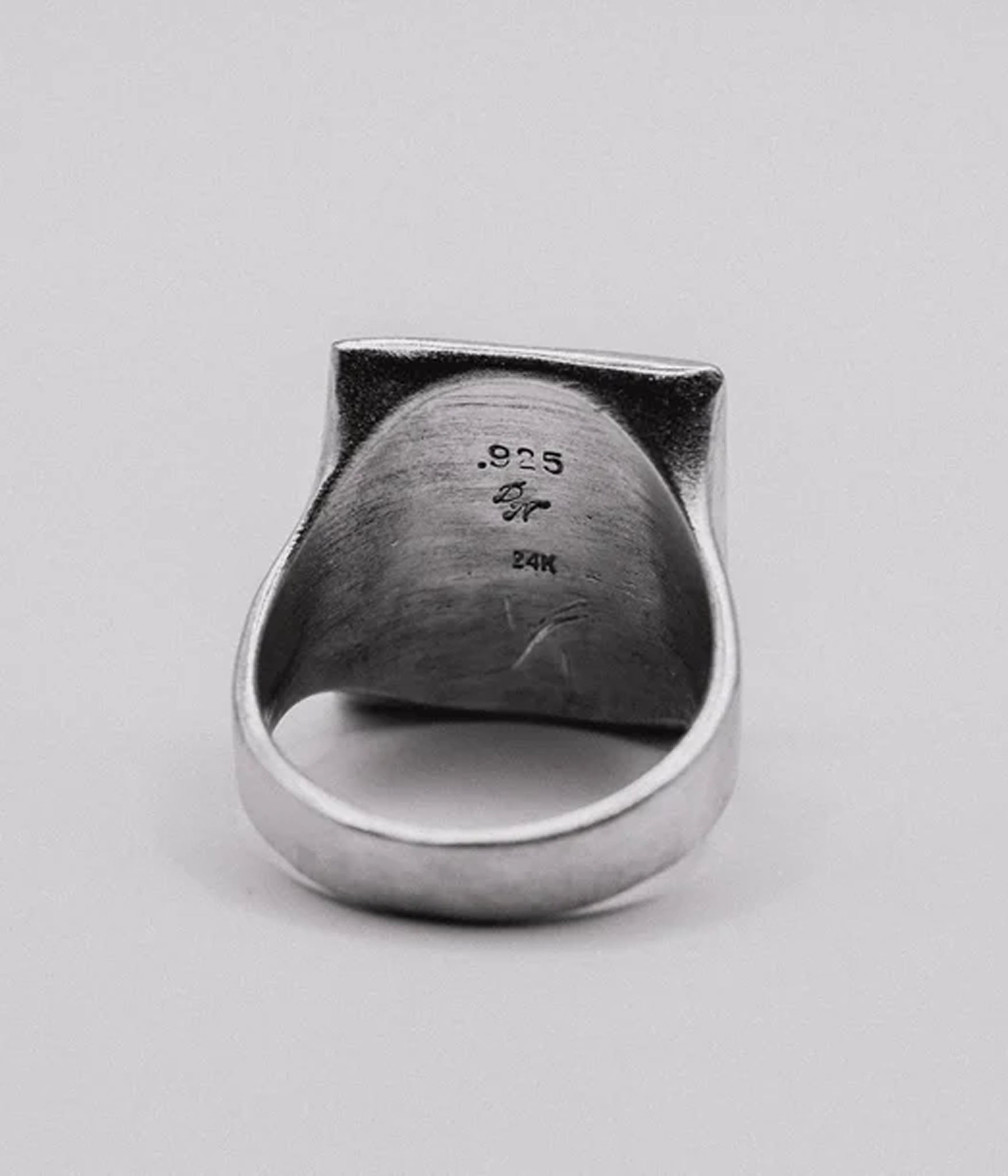 Silver ring with '925' and '24K' stamp on a light gray background