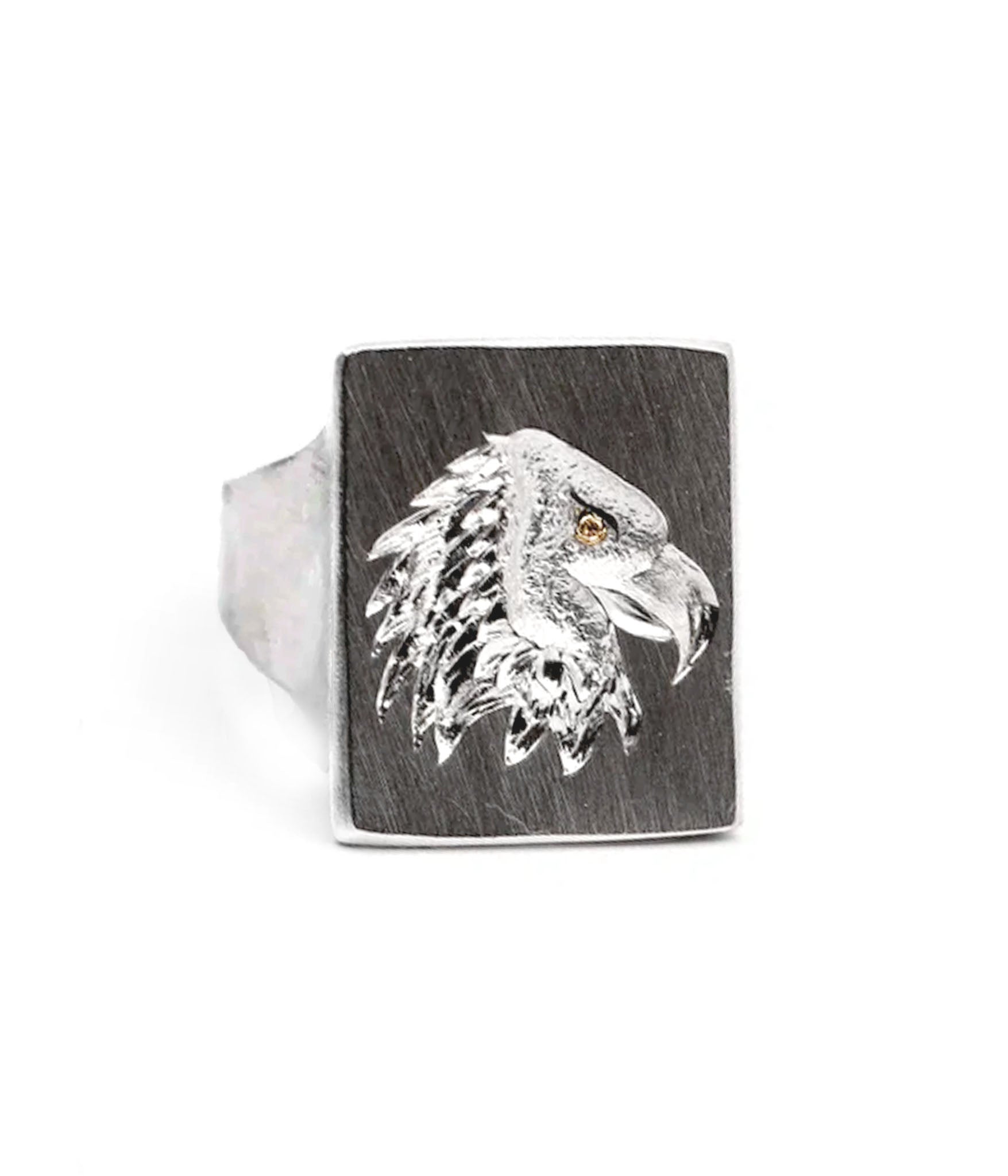 Silver ring with an eagle head design on a wooden band against a white background