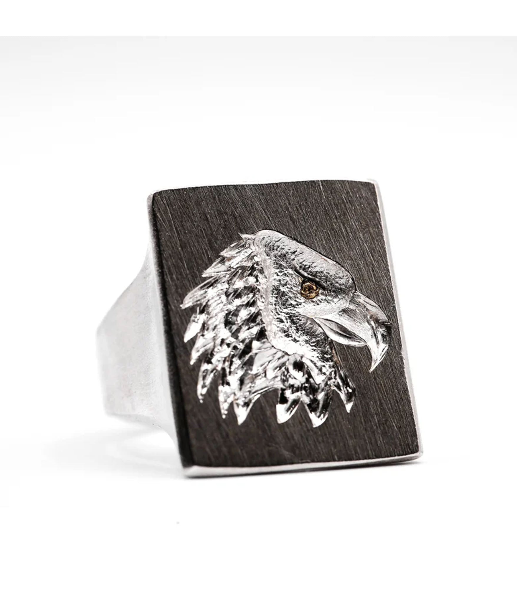 Silver eagle head design on a wooden ring with a white background