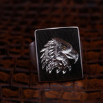 Silver eagle head ring on a dark brown leather background