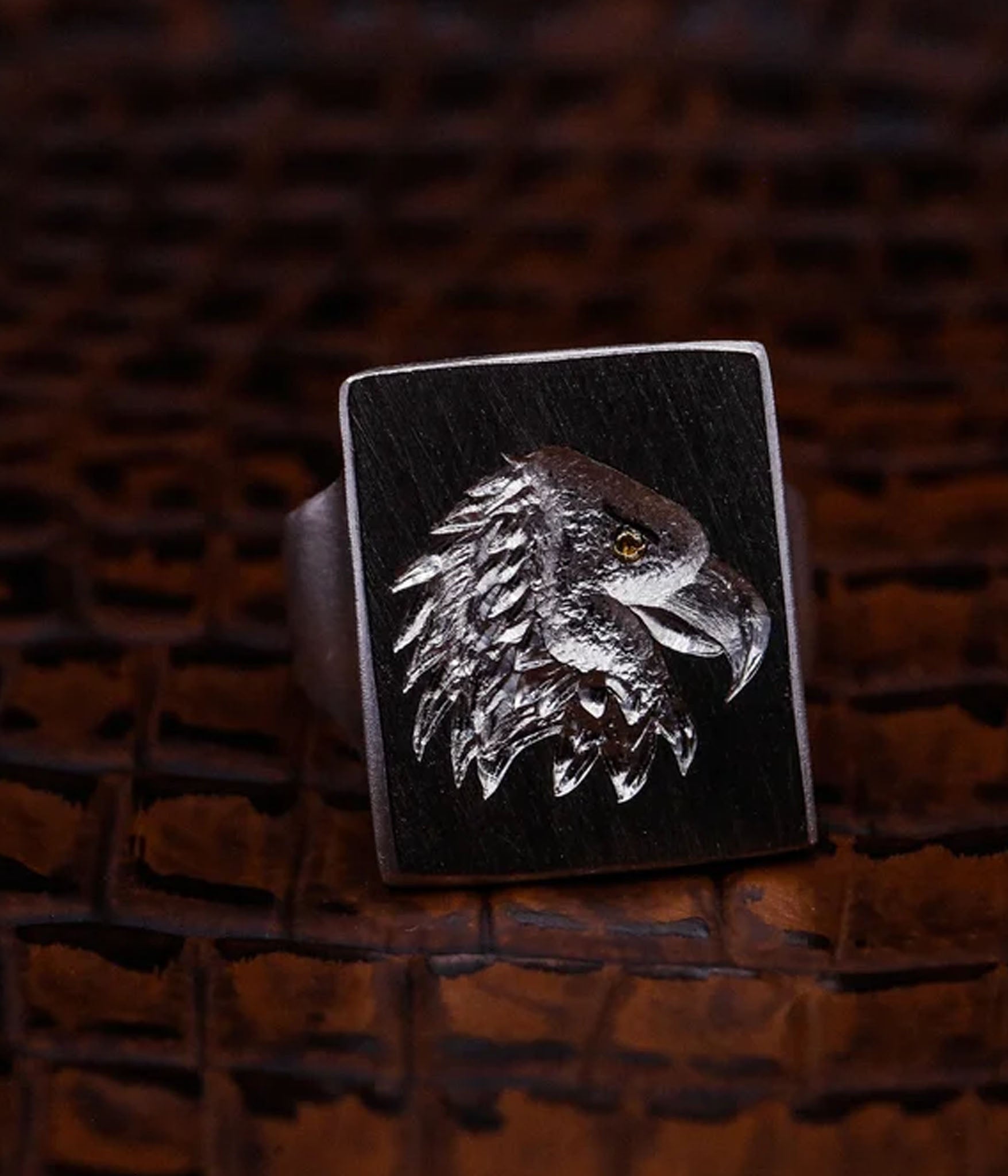 Silver eagle head ring on a dark brown leather background
