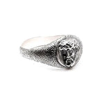 Silver ring with a textured band and central gemstone on a white background
