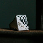 Checkered ring with a rose design on a dark surface