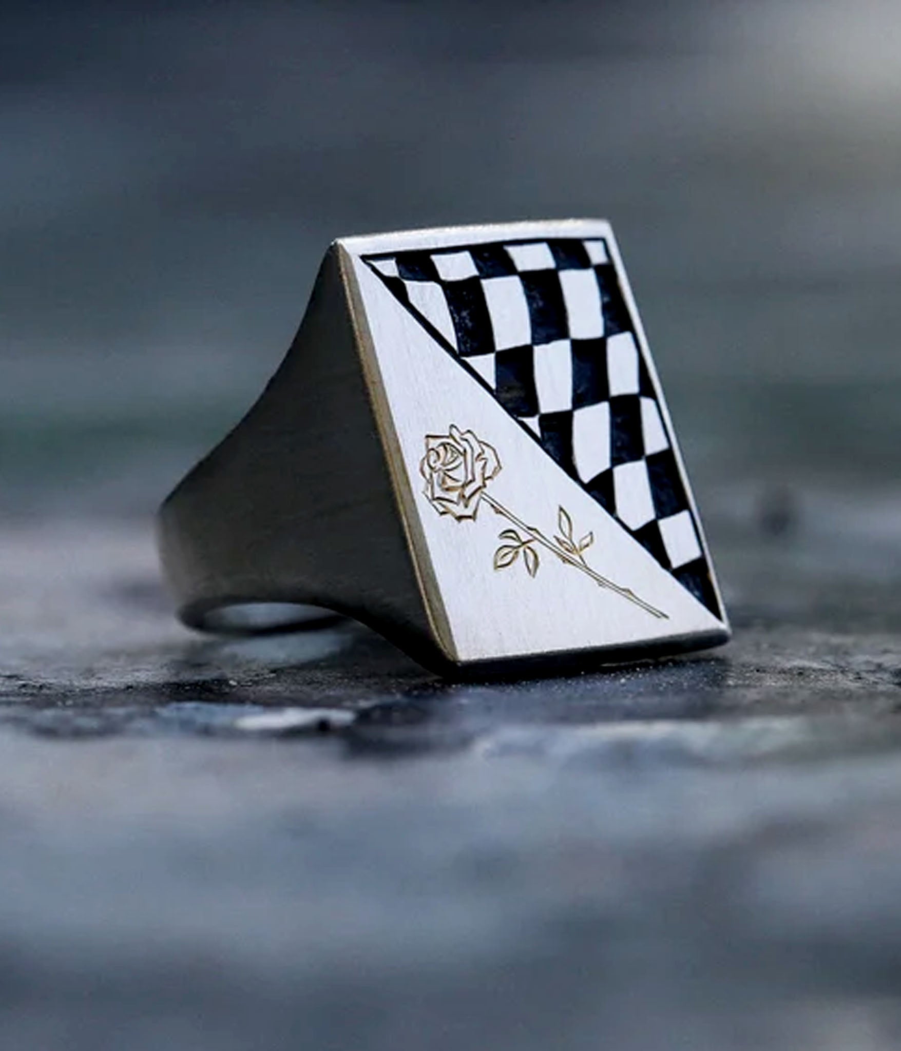 Checkered ring with a rose design on a dark surface