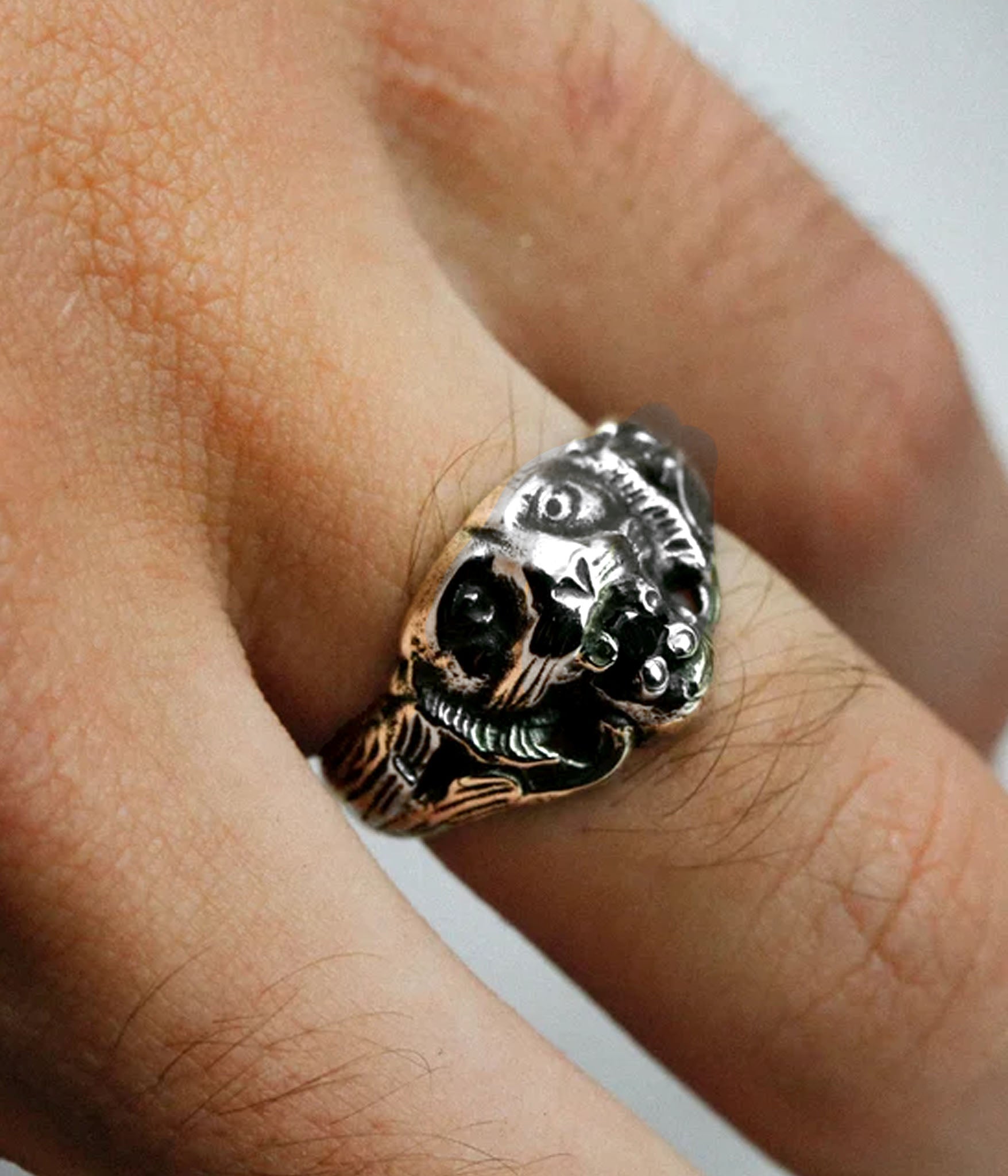 Silver skull ring on a finger with a blurred background