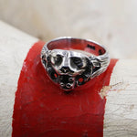 Silver ring with a detailed design on a red surface