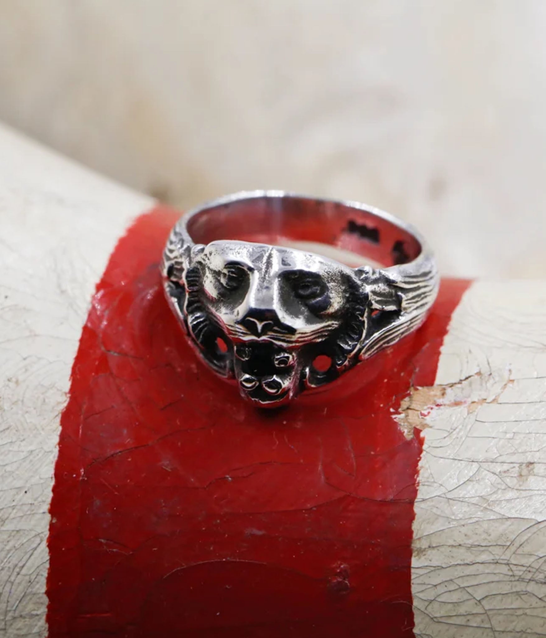 Silver ring with a detailed design on a red surface