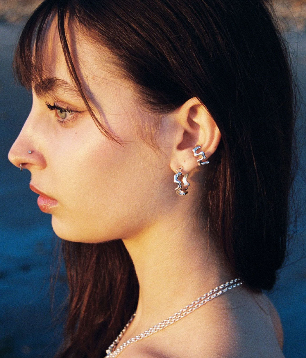 Woman wearing silver earrings with a blurred natural background