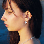 Woman wearing silver earrings with a blurred natural background