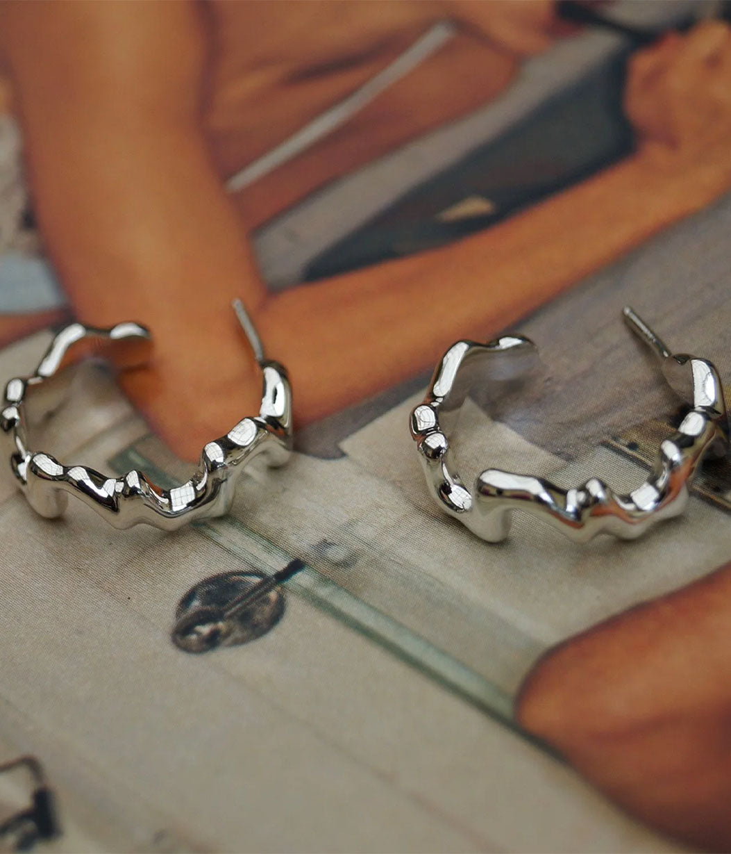 Silver hoop earrings on a wooden surface with a blurred background