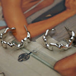 Silver hoop earrings on a wooden surface with a blurred background