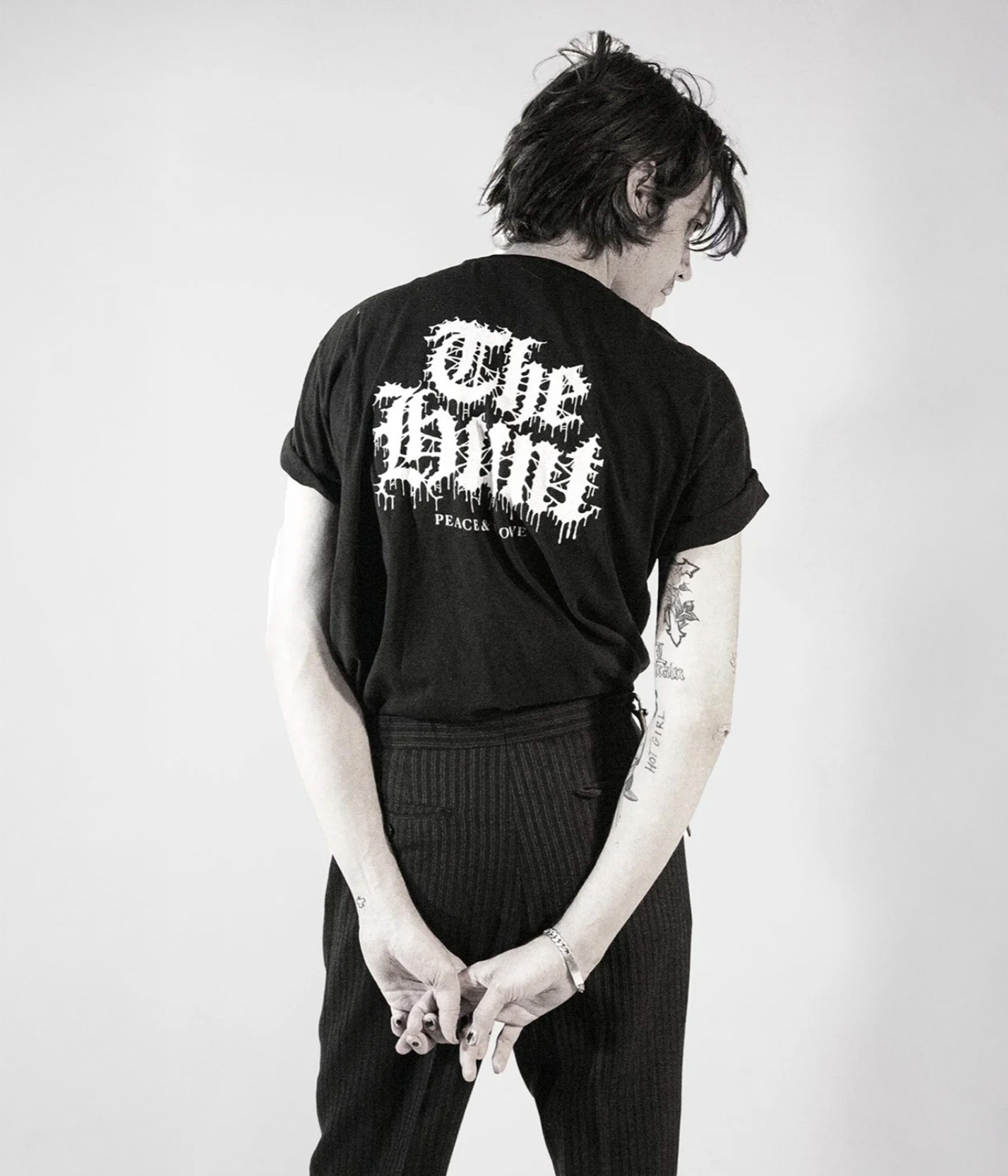 Person wearing a black t-shirt with 'The White' logo on the back, standing against a plain background.