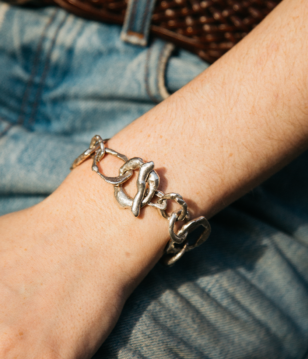 Silver chain bracelet on a wrist with denim background