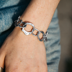 Silver chain bracelet on a wrist with a blurred denim background
