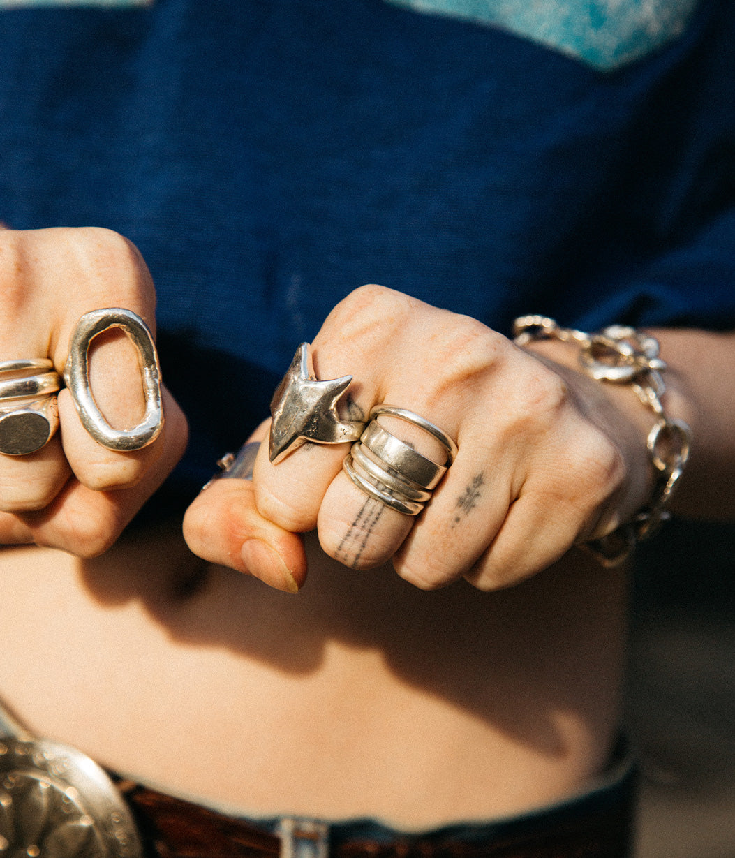Close-up of two hands with multiple silver rings on fingers and a bracelet on wrist.