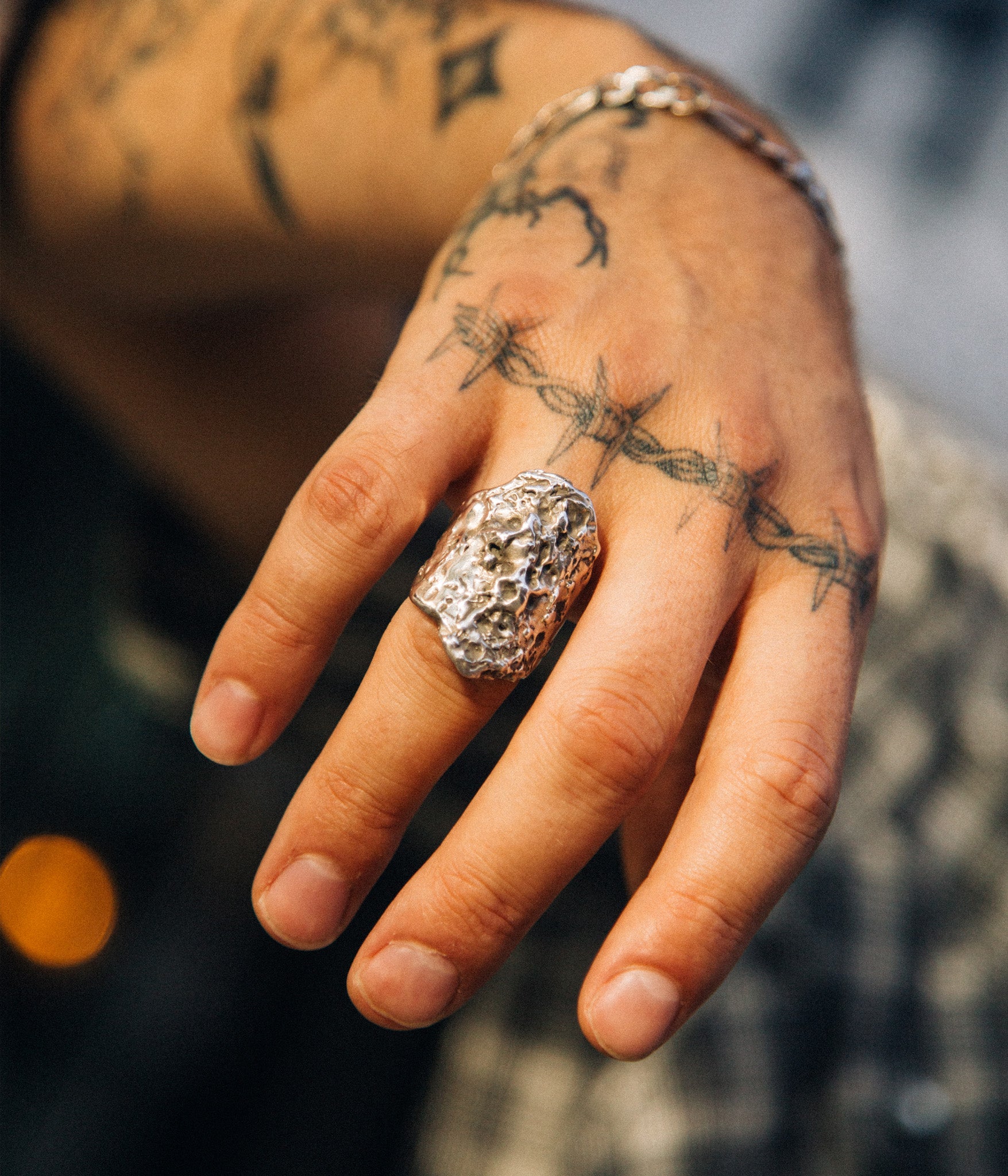 Hand with a textured silver ring on a blurred background