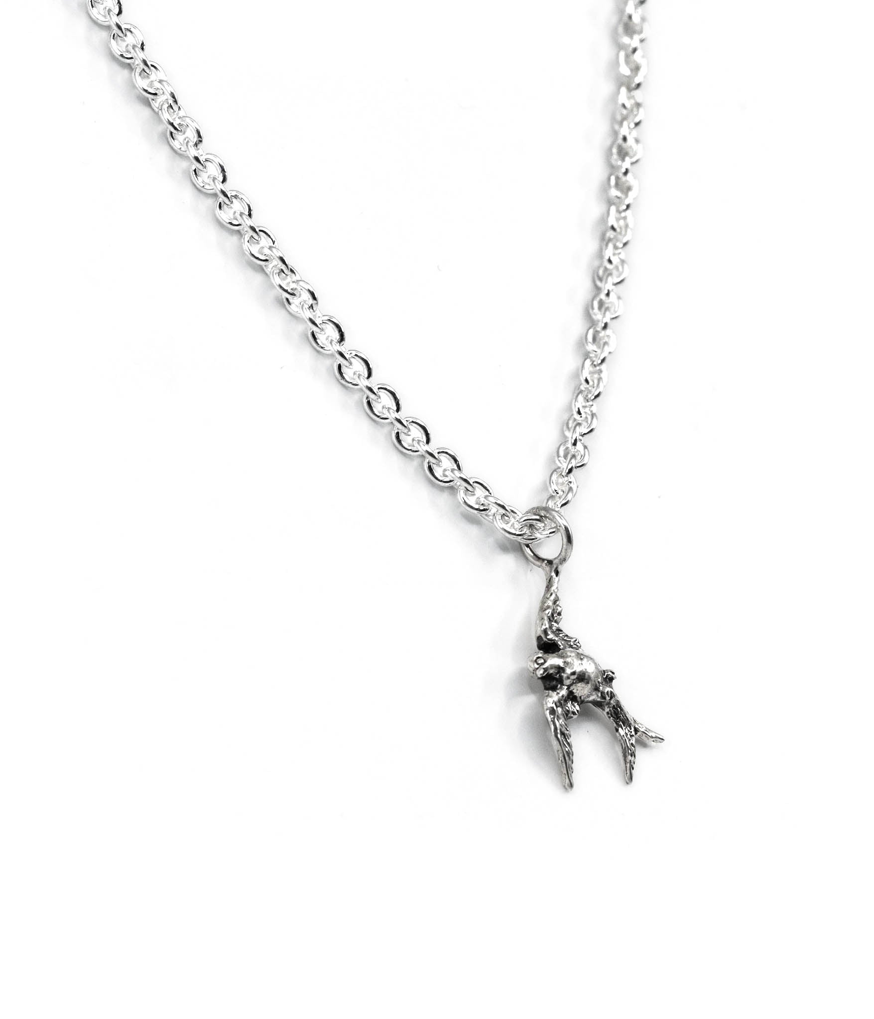 Silver necklace with a small bird pendant on a white background