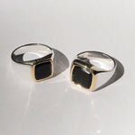 Two silver rings with black stones on a light gray background