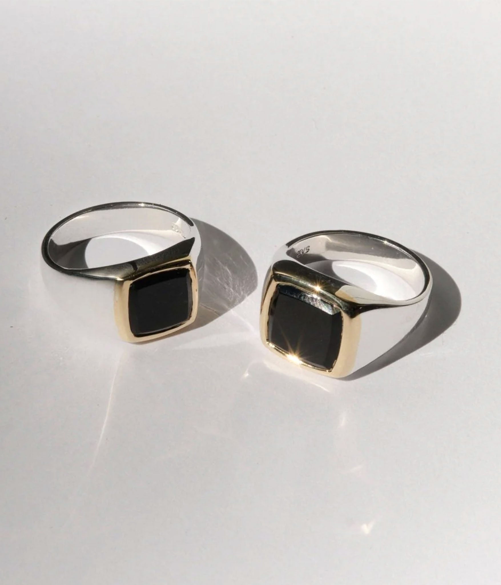 Two silver rings with black stones on a light gray background