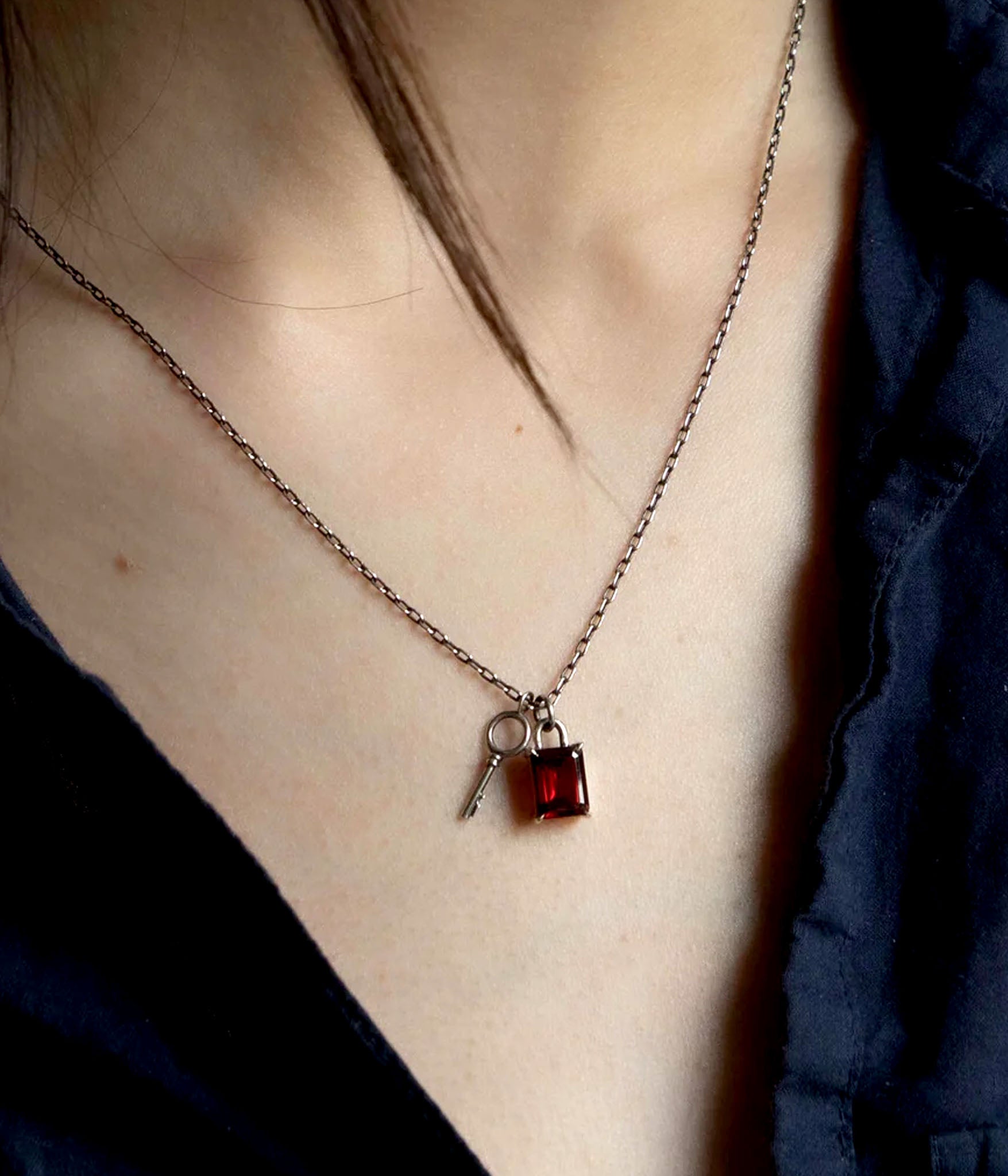 Garnet padlock and key necklace worn on model – sterling silver chain with deep red gemstone and symbolic key charm