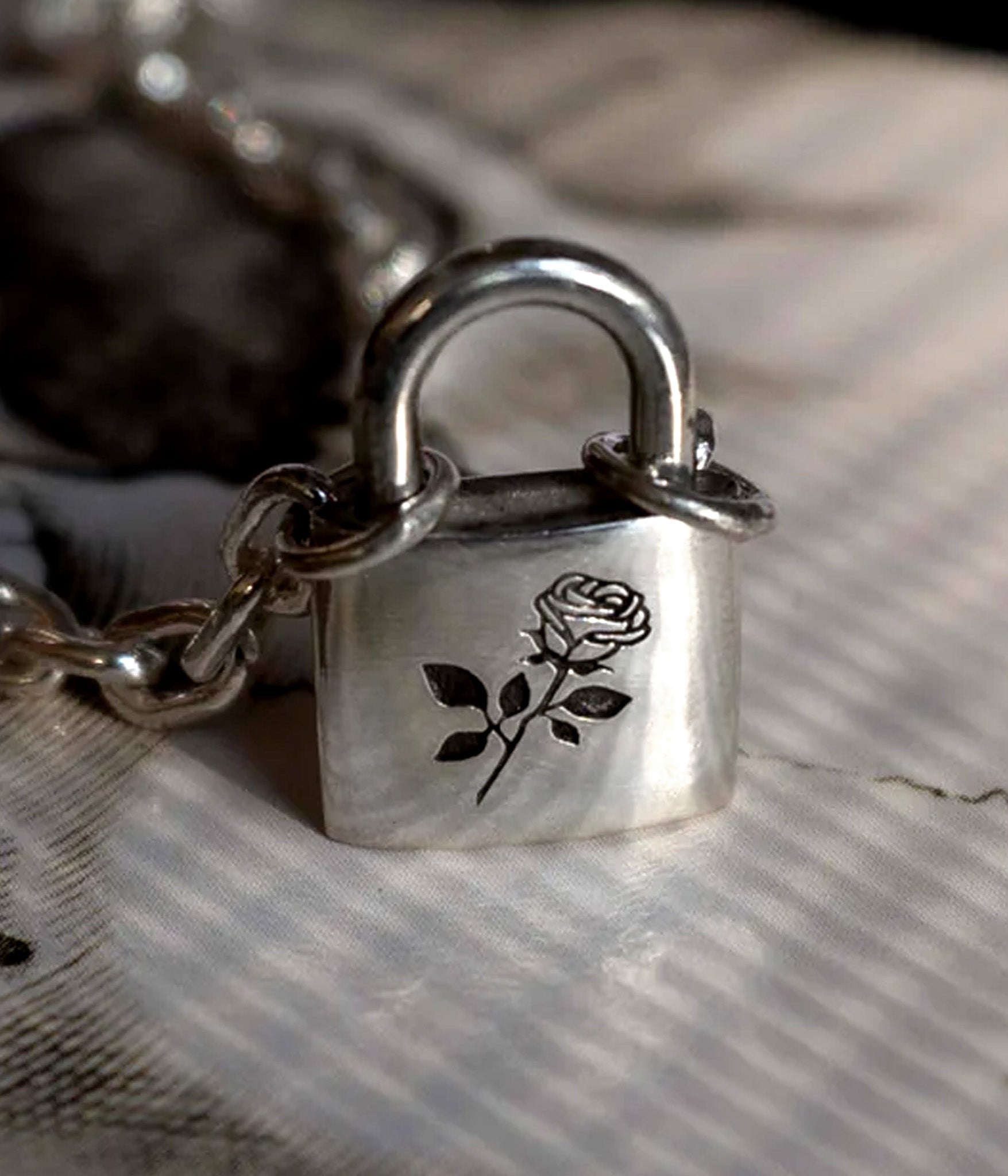 Sterling silver swallow padlock and key necklace displayed on white surface with oxidized chain