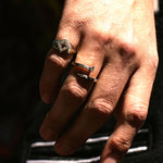 Editorial close-up of a hand wearing The Hunt’s Tough as Nails ring in sterling silver. Twisted nail form wraps the finger with raw, sculptural intent. Harsh directional lighting and shadow.