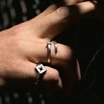 Editorial close-up of a hand wearing The Hunt’s Tough as Nails ring in sterling silver. Twisted nail form wraps the finger with raw, sculptural intent. Harsh directional lighting and shadow.