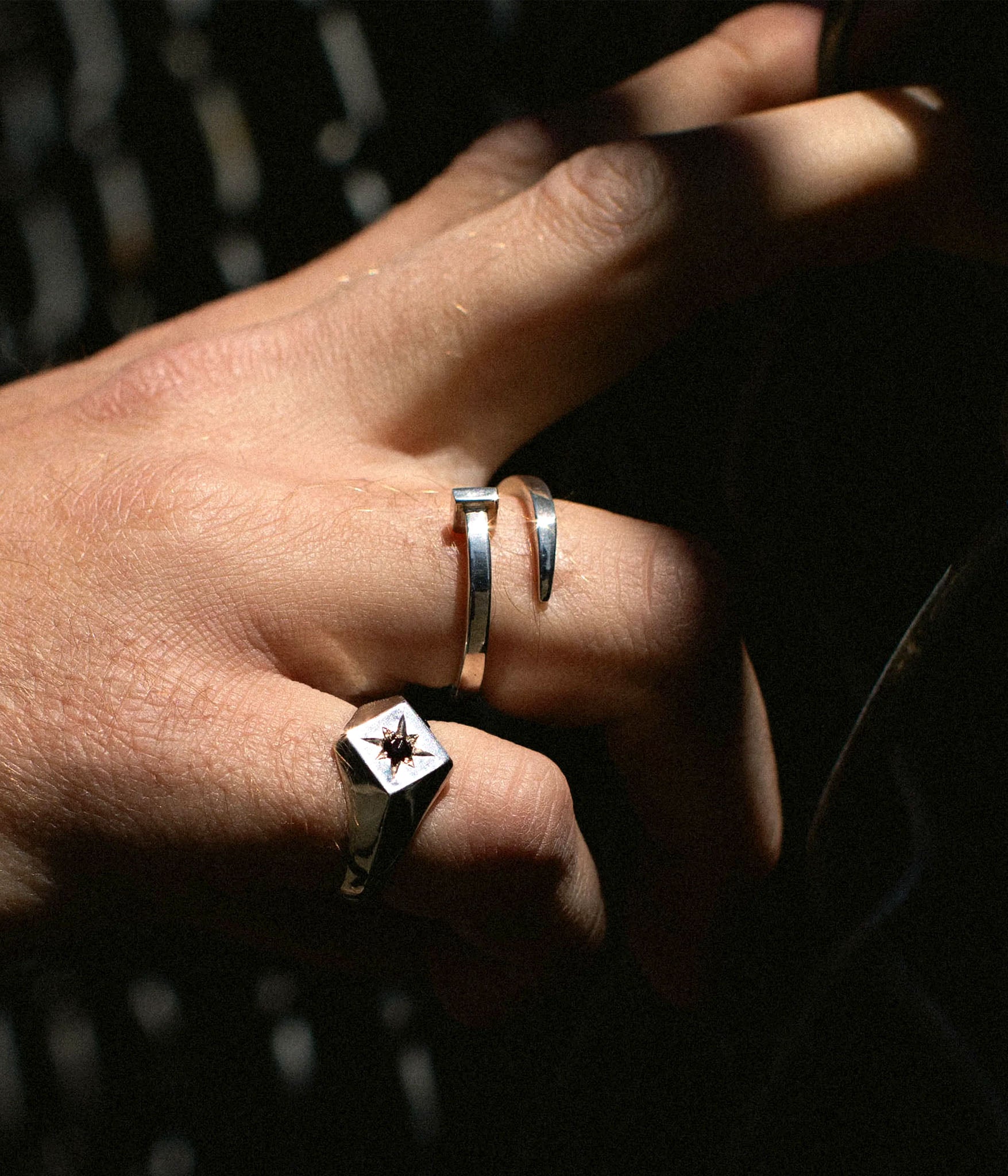 Editorial close-up of a hand wearing The Hunt’s Tough as Nails ring in sterling silver. Twisted nail form wraps the finger with raw, sculptural intent. Harsh directional lighting and shadow.