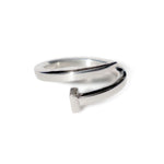 Close-up of handcrafted sterling silver nail ring twisted into an open design, photographed on a white studio background.