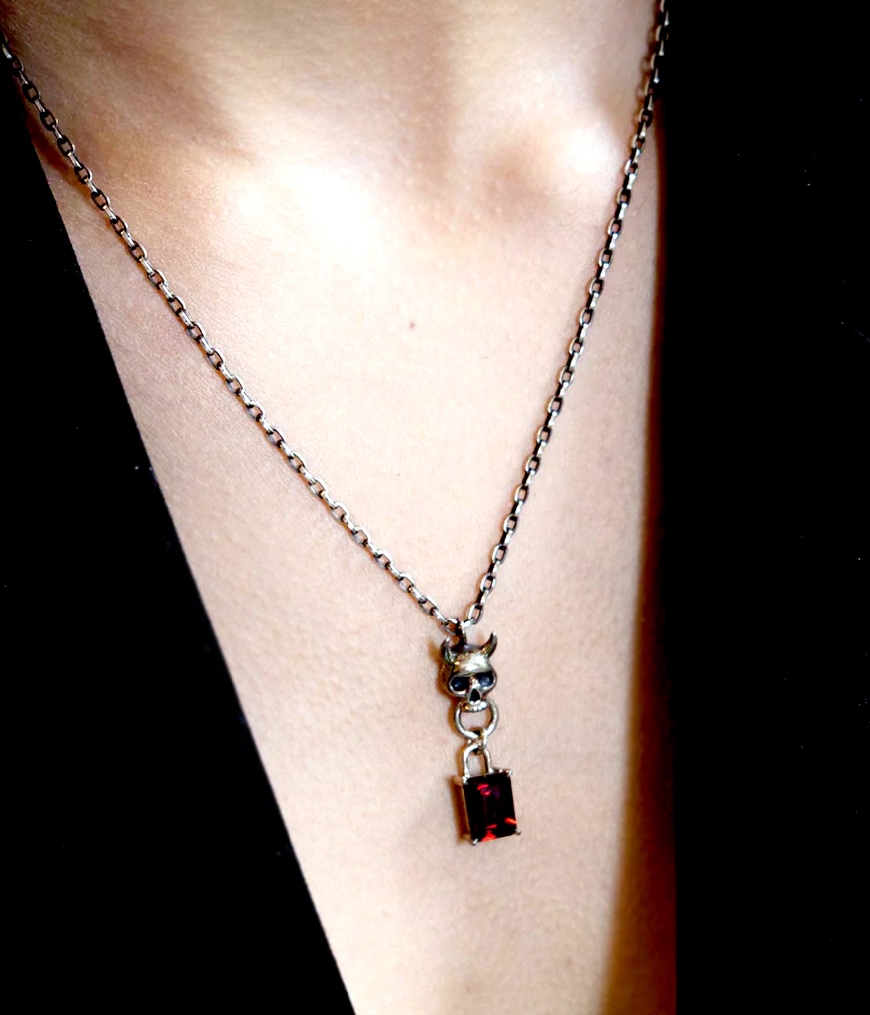 Sterling silver skull pendant necklace with door knocker and garnet lock detail on model 