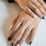 Traditional round sterling silver signet ring with snake engraving by Futaba for The Hunt on females hand with painted nails in soft light
