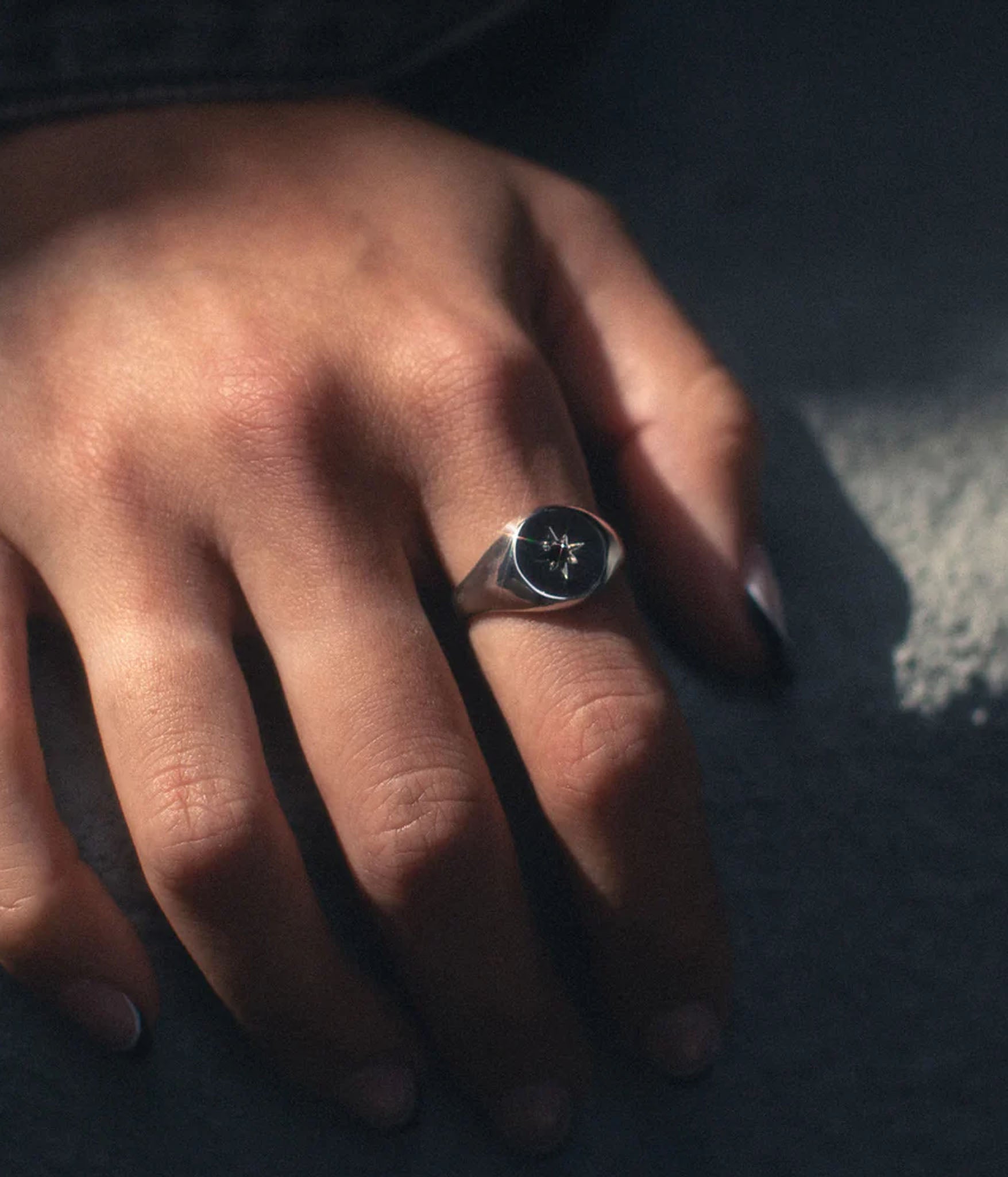 Close-up of polished silver starburst ring reflecting light — handcrafted artisan signet by The Hunt NYC