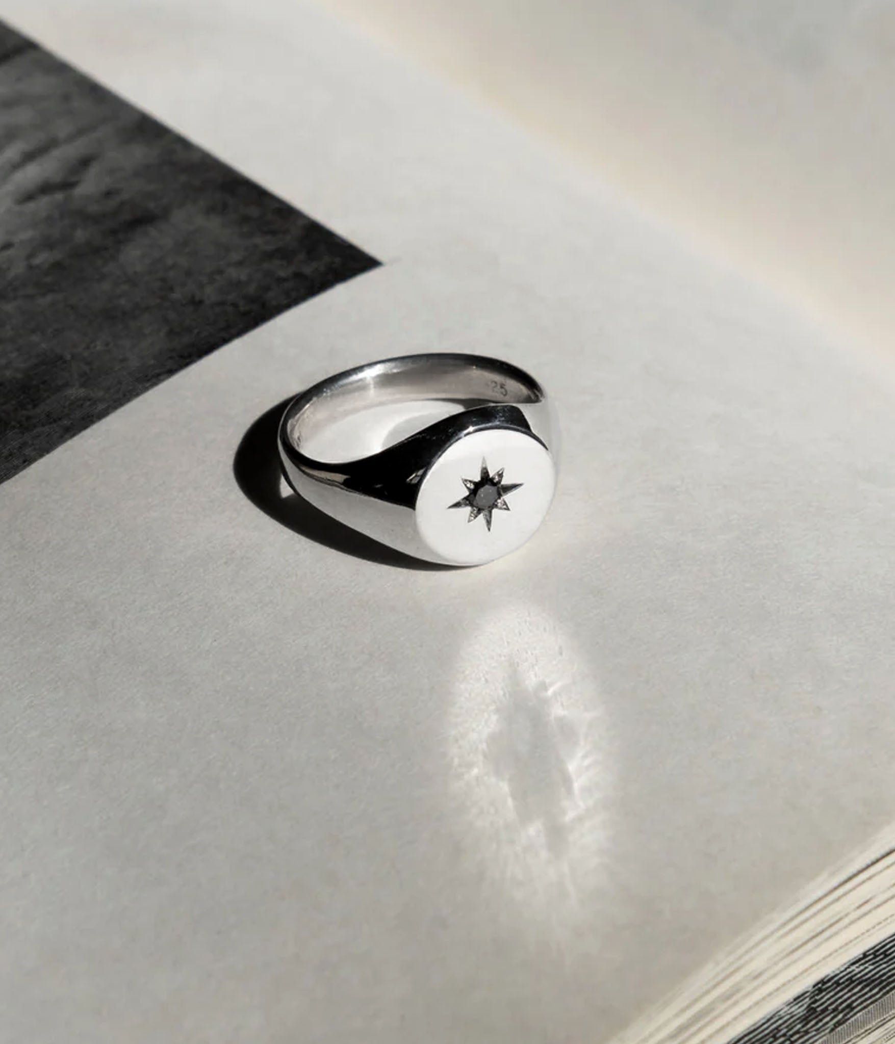 Sterling silver North Star signet ring on matte paper with sharp shadow detail — minimalist celestial jewelry by The Hunt NYC