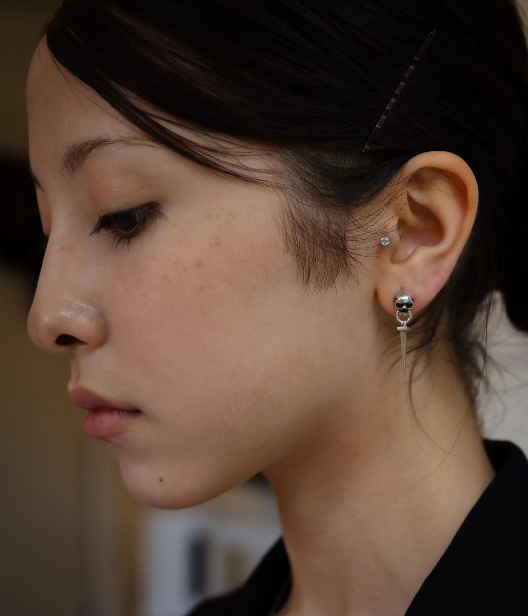 Side profile of model wearing Skull Door Knocker Nail Earring with skull and nail pendant in sterling silver on silver stud. Lightweight unisex design.
