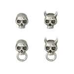 Flat lay of four sterling silver skull stud earrings in varying styles: classic skull, horned Oni skull, skull with ring, and horned Oni skull with ring. 
